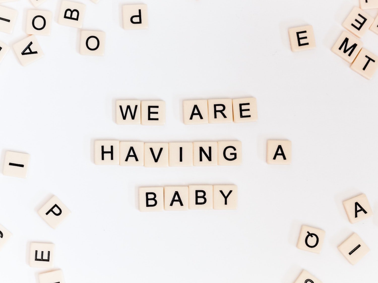 "We are having a baby" spelled out with Scrabble pieces